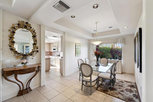 tiled dining room featuring a raised ceiling