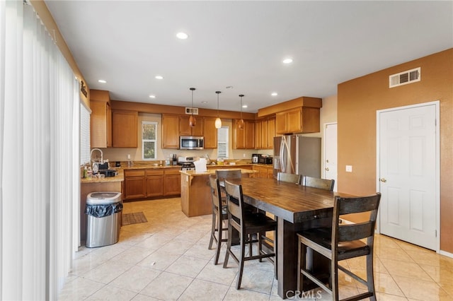 kitchen featuring light tile patterned flooring, sink, appliances with stainless steel finishes, a kitchen island, and pendant lighting