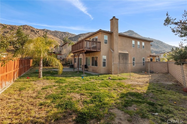 back of house with a mountain view and a lawn