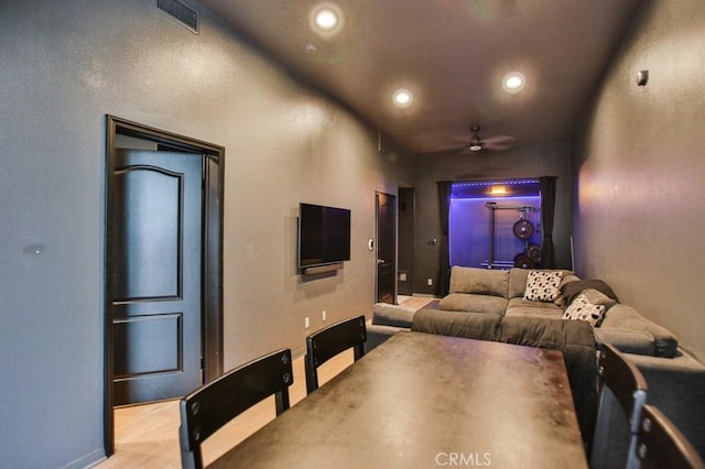 home theater room with ceiling fan and light hardwood / wood-style flooring