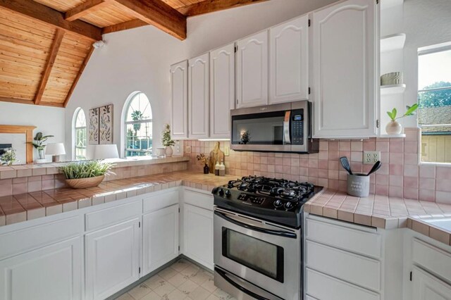 kitchen featuring wood ceiling, stainless steel appliances, tile countertops, and white cabinets