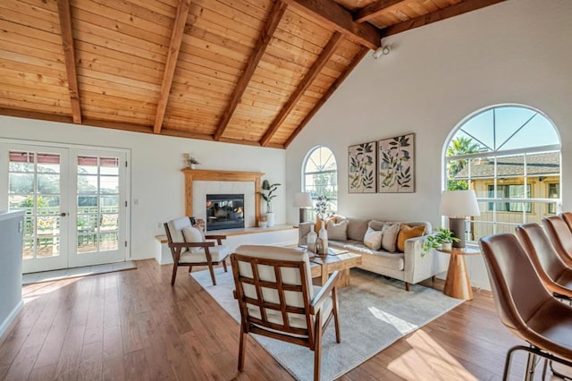 living room featuring a tiled fireplace, wood ceiling, light wood-type flooring, and french doors