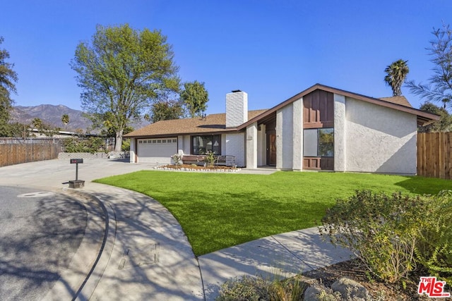 view of front of home featuring a garage, a mountain view, and a front lawn