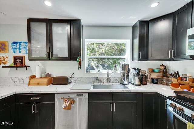 kitchen with light stone counters, stainless steel appliances, and sink