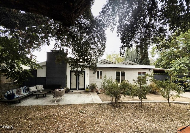 back of property with outdoor lounge area and a patio area