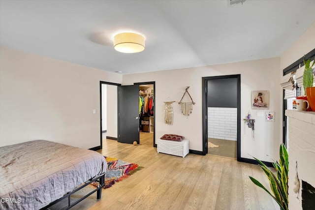 bedroom with a spacious closet, light hardwood / wood-style flooring, a closet, and ensuite bathroom