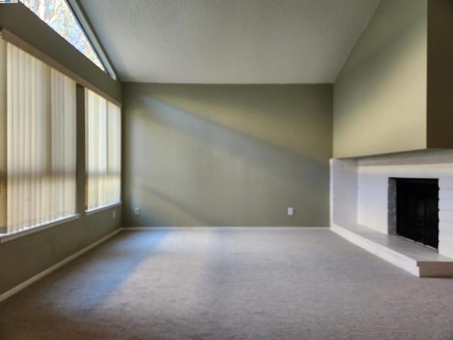 unfurnished living room with carpet floors, a fireplace, and vaulted ceiling