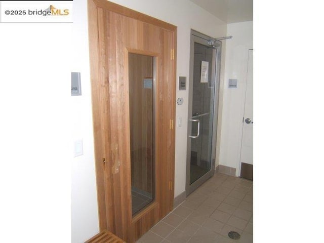 bathroom with walk in shower, elevator, and tile patterned flooring