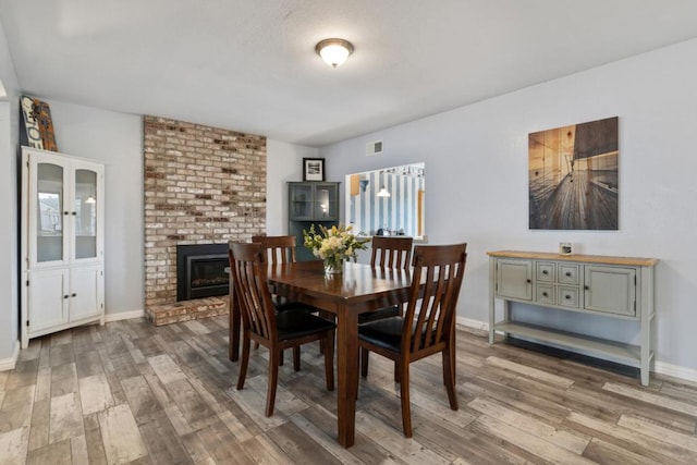 dining space featuring a brick fireplace and hardwood / wood-style flooring