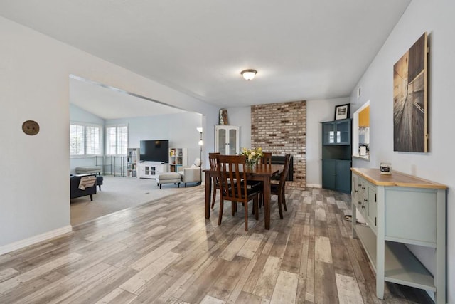 dining area featuring vaulted ceiling and light wood-type flooring