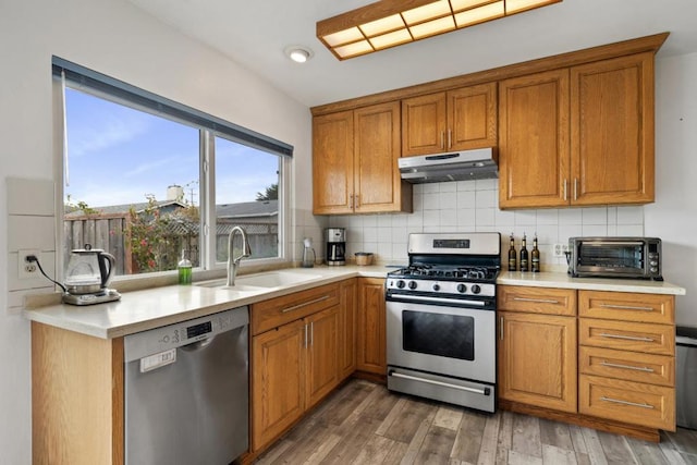 kitchen with dark hardwood / wood-style flooring, sink, backsplash, and stainless steel appliances