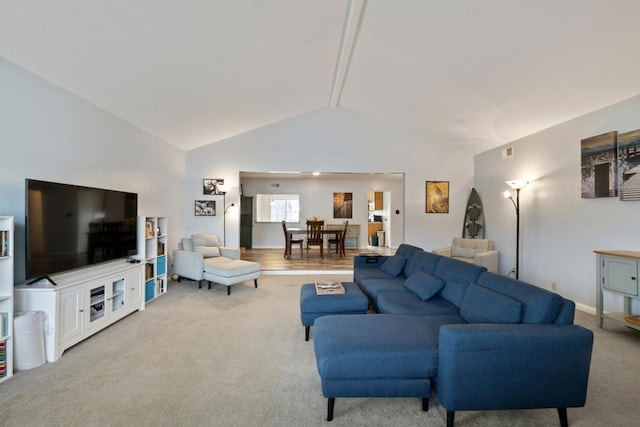 carpeted living room with high vaulted ceiling