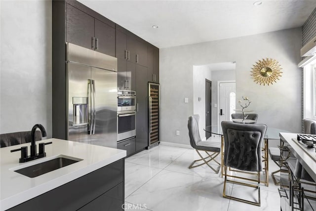 kitchen featuring appliances with stainless steel finishes, sink, wine cooler, and dark brown cabinetry