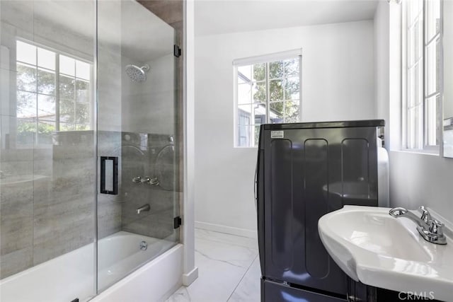 bathroom with bath / shower combo with glass door, washer / clothes dryer, and sink