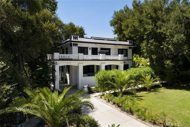 view of front facade featuring a balcony and a front lawn