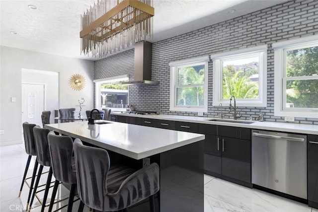 kitchen with sink, stainless steel appliances, an island with sink, and wall chimney exhaust hood