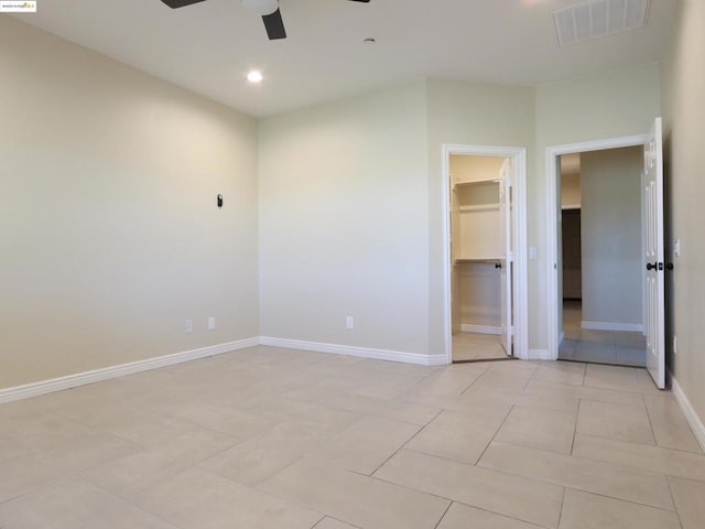 unfurnished bedroom with light tile patterned floors, a walk in closet, a closet, and ceiling fan