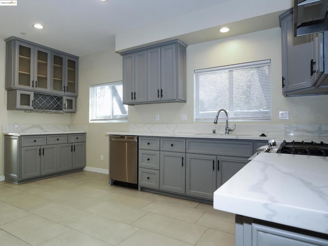 kitchen with dishwasher, light stone countertops, sink, and gray cabinetry