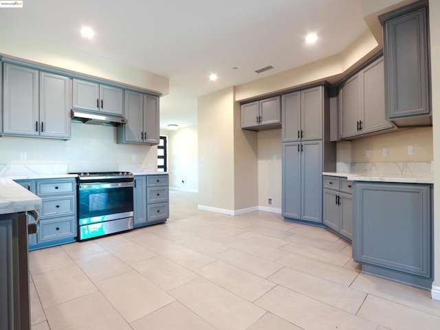 kitchen featuring gray cabinets, light tile patterned floors, stainless steel range, and light stone counters