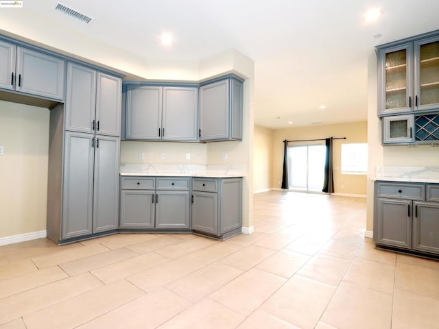 kitchen with light tile patterned flooring, gray cabinets, and light stone countertops