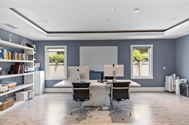 office with light wood-type flooring and a tray ceiling