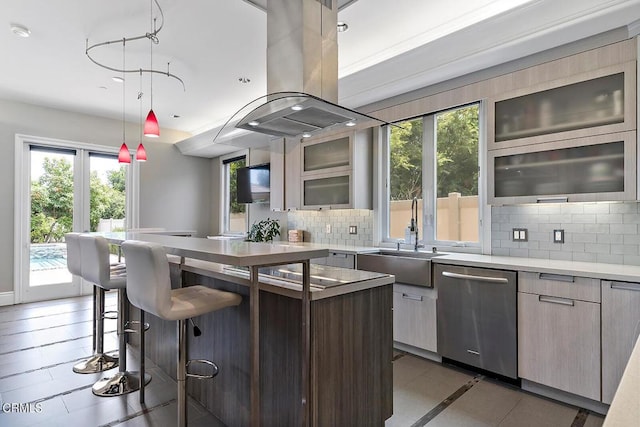 kitchen with island range hood, tasteful backsplash, sink, dark tile patterned floors, and stainless steel dishwasher