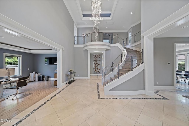 entrance foyer with light tile patterned flooring, plenty of natural light, a notable chandelier, and crown molding