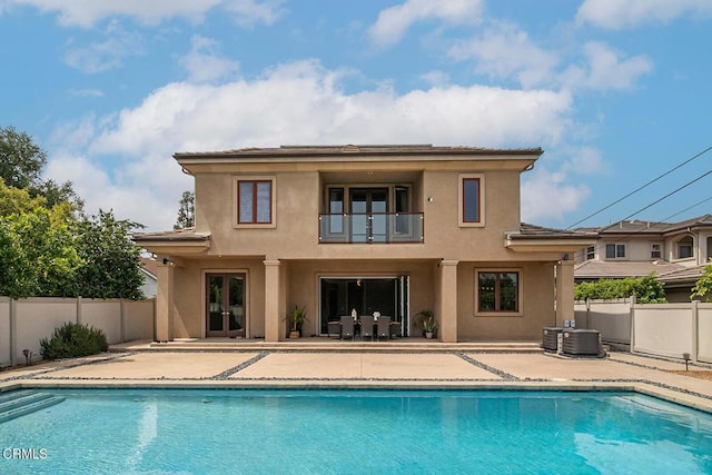 back of house featuring a balcony, a fenced in pool, and a patio area