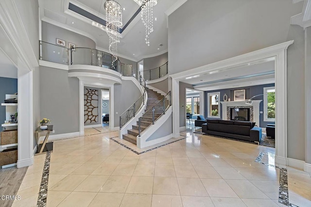 entrance foyer featuring crown molding, light tile patterned floors, a towering ceiling, and a high end fireplace