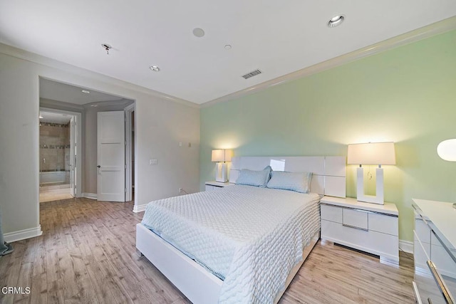 bedroom featuring ornamental molding, ensuite bathroom, and light hardwood / wood-style flooring