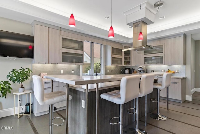 kitchen with light brown cabinets, pendant lighting, and a kitchen bar