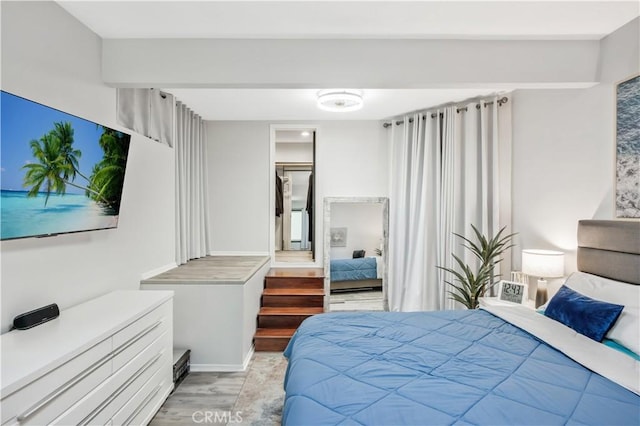 bedroom with a spacious closet and light hardwood / wood-style floors