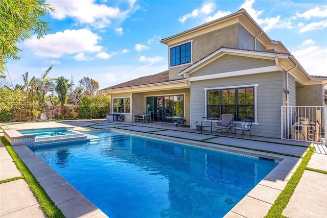 rear view of property featuring a swimming pool with hot tub and a patio