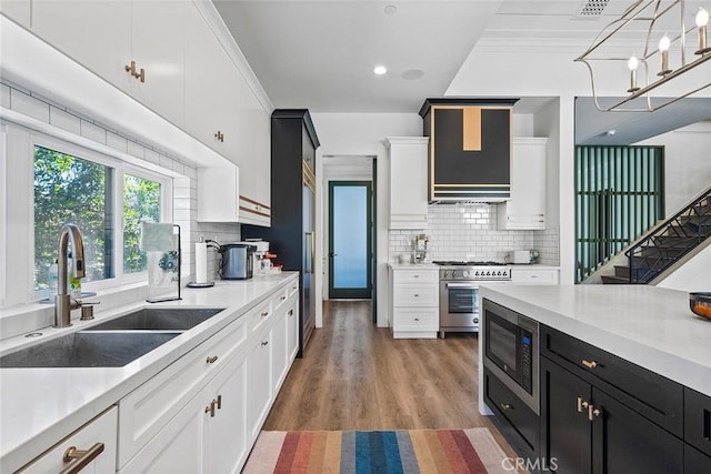 kitchen featuring sink, hardwood / wood-style flooring, stainless steel range, built in microwave, and decorative light fixtures