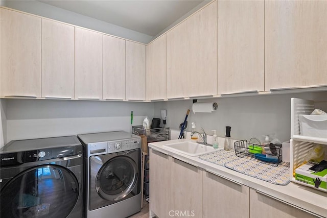 laundry area with sink, washing machine and dryer, and cabinets