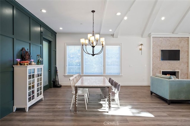 dining area with beamed ceiling, a notable chandelier, dark hardwood / wood-style flooring, and a fireplace