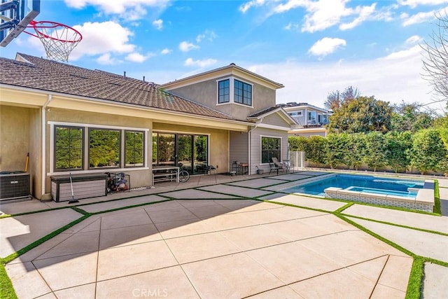 rear view of property featuring a swimming pool with hot tub, a patio, and central AC unit