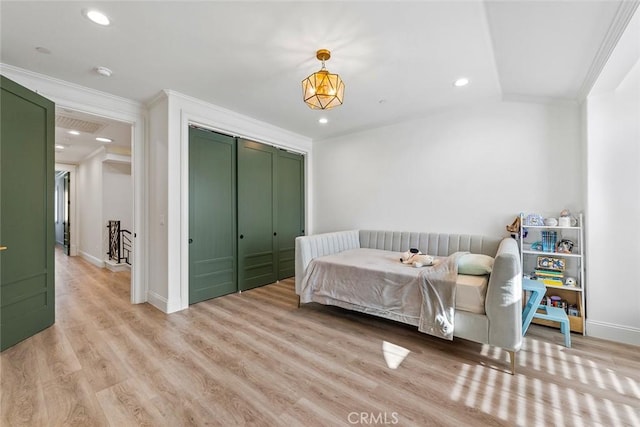 bedroom with crown molding, light hardwood / wood-style flooring, and a closet