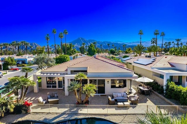 back of house with a fenced in pool, a mountain view, an outdoor hangout area, and a patio area