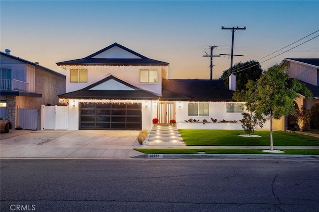 view of property with a garage and a lawn