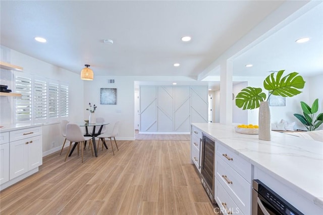 kitchen featuring light stone counters, a barn door, beverage cooler, light hardwood / wood-style floors, and white cabinets