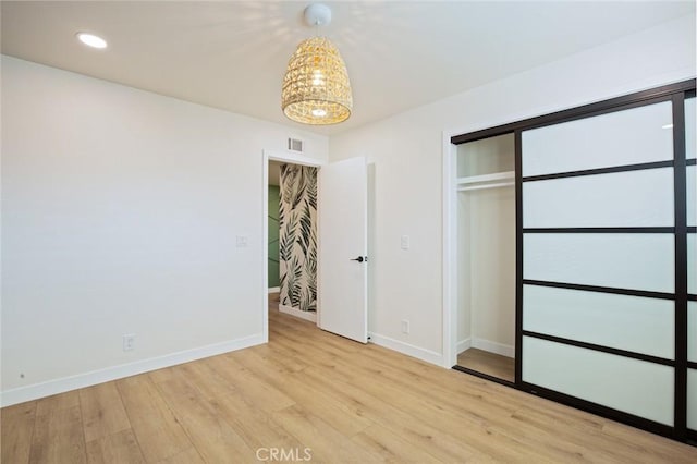 unfurnished bedroom featuring light wood-type flooring and a closet