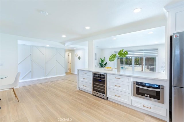 kitchen featuring white cabinetry, stainless steel appliances, beverage cooler, and light hardwood / wood-style flooring