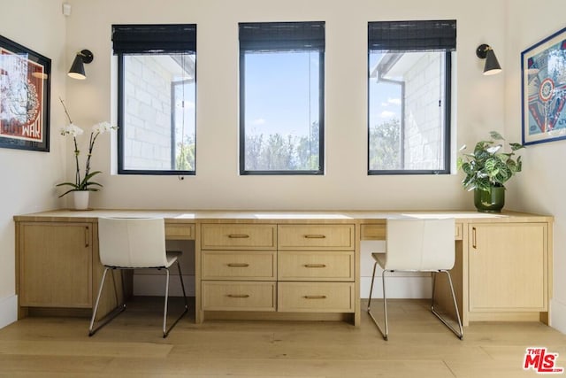 home office featuring light hardwood / wood-style flooring and built in desk