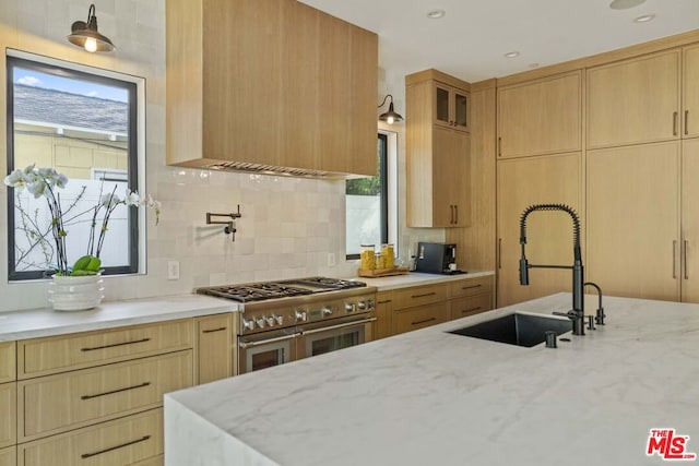 kitchen with range with two ovens, light stone countertops, and sink