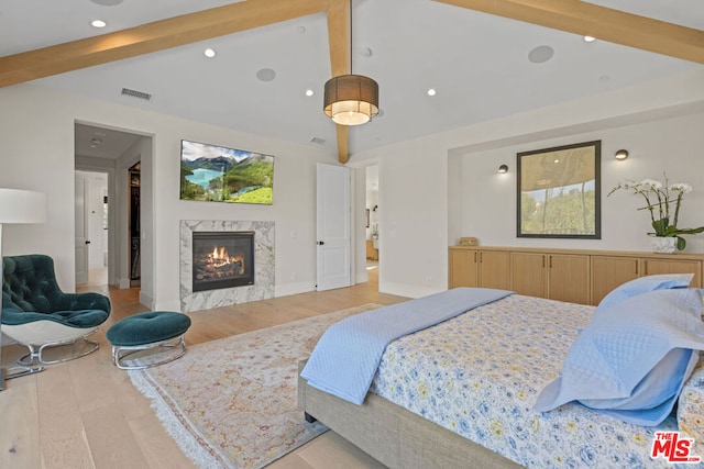 bedroom with vaulted ceiling with beams, light hardwood / wood-style floors, and a premium fireplace