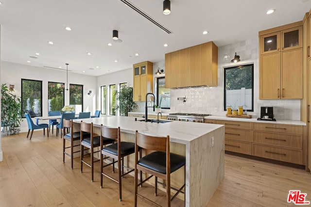 kitchen featuring a kitchen bar, sink, a kitchen island with sink, and light wood-type flooring