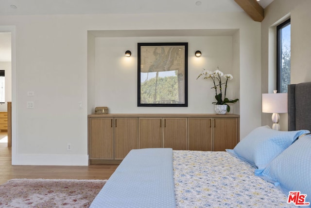 bedroom with beam ceiling and light wood-type flooring