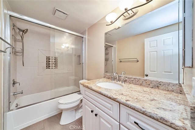 full bathroom featuring enclosed tub / shower combo, vanity, toilet, and hardwood / wood-style floors