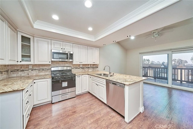 kitchen with stainless steel appliances, sink, white cabinets, and kitchen peninsula